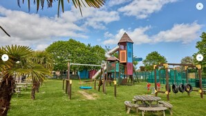 Un parque infantil con tobogán, columpios y una estructura para escalar.