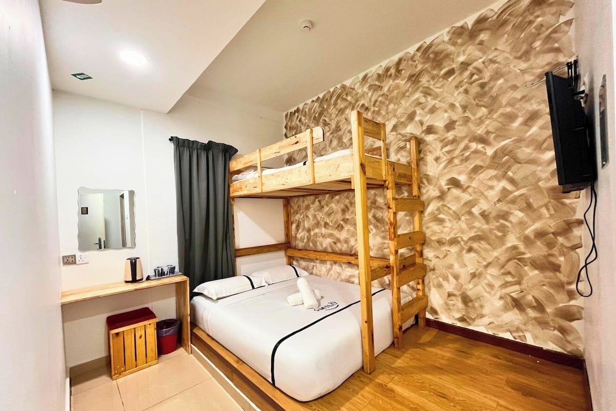 A bunk bed room with a wooden ladder, a desk with a mirror, and a wall with a textured pattern.