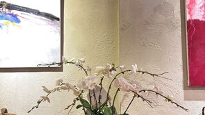 A potted orchid on a tiled floor with a textured wall and a painting in the background. - Truong Giang Boutique Hotel (Thao Nguyen)