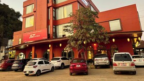 A red building with multiple windows and a J&T Express sign. There are several cars parked in front. - Truong Giang Boutique Hotel (Thao Nguyen)