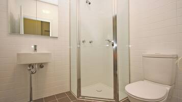 A bathroom with a glass-enclosed shower, a white sink, and a toilet.
