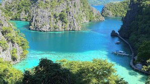 A coastal landscape with a prominent rocky island surrounded by turquoise waters. - Golden Anchor- Lodge (Coron)