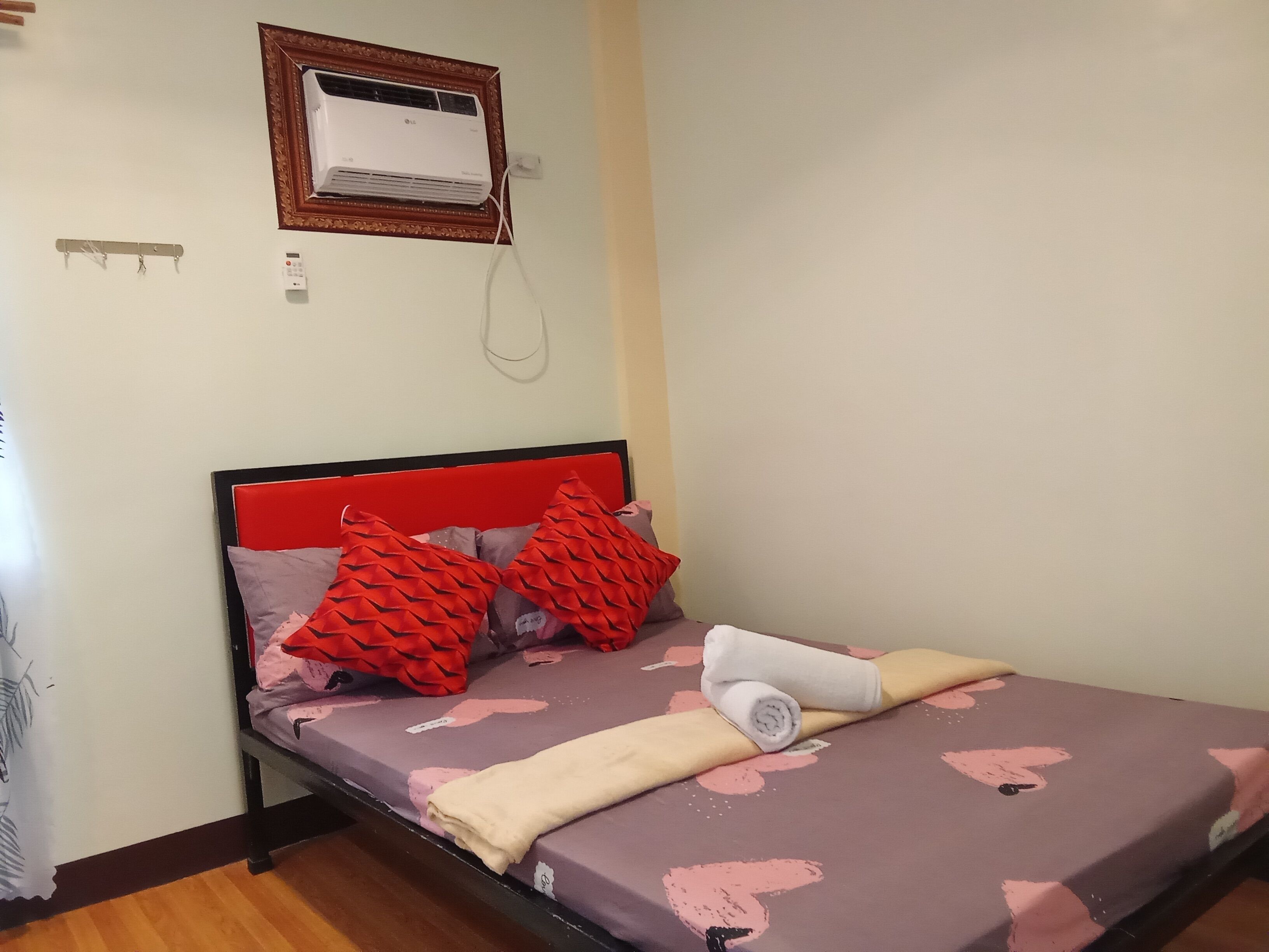 Un dormitorio con una cama, un cabecero rojo y un aire acondicionado instalado en la pared.