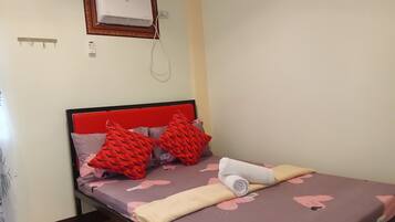 Un dormitorio con una cama, un cabecero rojo y un aire acondicionado instalado en la pared.