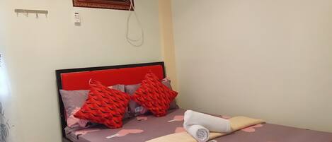 Une chambre à coucher avec un lit, une tête de lit rouge et un climatiseur fixé au mur.