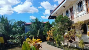 A residential building with a covered porch, surrounded by lush greenery and a clear blue sky. - Golden Anchor- Lodge (Coron)
