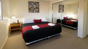 Ein Hotelzimmer mit einem großen Bett, einem Nachttisch, einem Spiegel und Bildern an den Wänden.