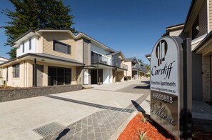 A modern two-story residential building with a sign indicating 'Cardiff Executive Apartments'. - Two Bedroom Apartment (Cardiff)
