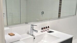 A modern bathroom with a large mirror, a white sink, and a black vanity. - Two Bedroom Apartment (Charlestown)