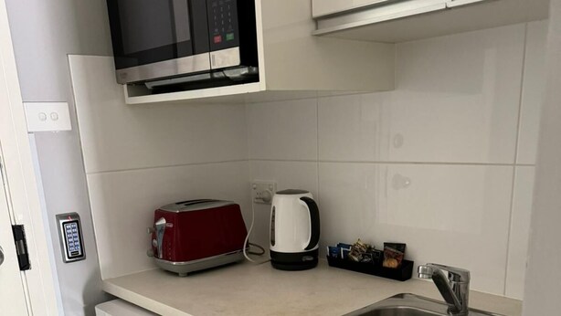 Eine kompakte Küche mit Mikrowelle, Toaster, Wasserkocher und Spüle.