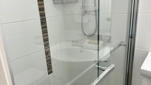 Eine Duschkabine mit Glas, ein weißes Waschbecken und eine Handbrause.