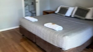 Ein Schlafzimmer mit einem Bett, Kissen, einem Nachttisch und einer Tür zu einem Badezimmer.