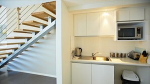 A modern kitchen with white cabinets, a stainless steel sink, a microwave, and a toaster.