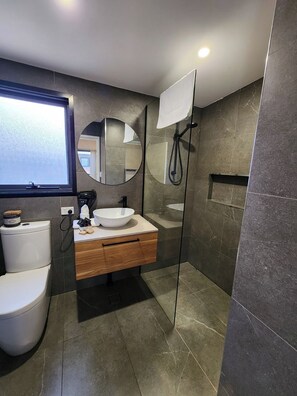 Features a sleek tile design, white toilet, and glass-enclosed shower area.