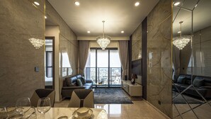 A modern living room with a marble floor, a dining area with a table set for a meal, and a large chandelier. - Genius Saigon - The MarQ District 1 (Ho Chi Minh City)