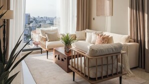 A modern living room with a large window, a sofa set, a coffee table, and a pendant light. - Genius Saigon - The MarQ District 1 (Ho Chi Minh City)