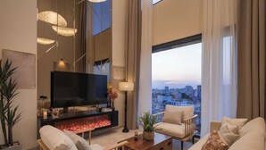 A modern living room with a flat-screen TV, a fireplace, and a sofa. - Genius Saigon - The MarQ District 1 (Ho Chi Minh City)
