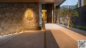 A modern building entrance with a stone facade, a wooden ceiling, and a sign reading "TOWER B". - Genius Saigon - The MarQ District 1 (Ho Chi Minh City)