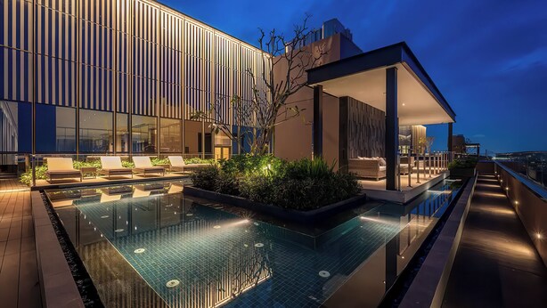 A modern hotel with a rooftop infinity pool, lounge area, and a view of the city skyline at dusk. - Genius Saigon - The MarQ District 1 (Ho Chi Minh City)