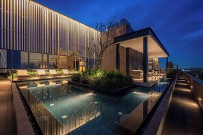 A modern hotel with a rooftop infinity pool, lounge area, and a view of the city skyline at dusk. - Genius Saigon - The MarQ District 1 (Ho Chi Minh City)