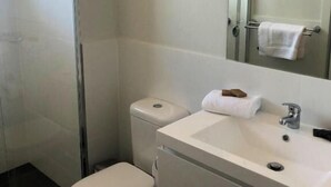 A modern bathroom with a toilet, sink, and shower. - Two Bedroom Apartment (Waratah West)
