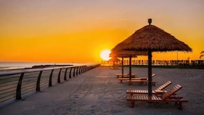 A beach with a wooden fence, a thatched umbrella, and wooden lounge chairs. - home at beach (Beihai)