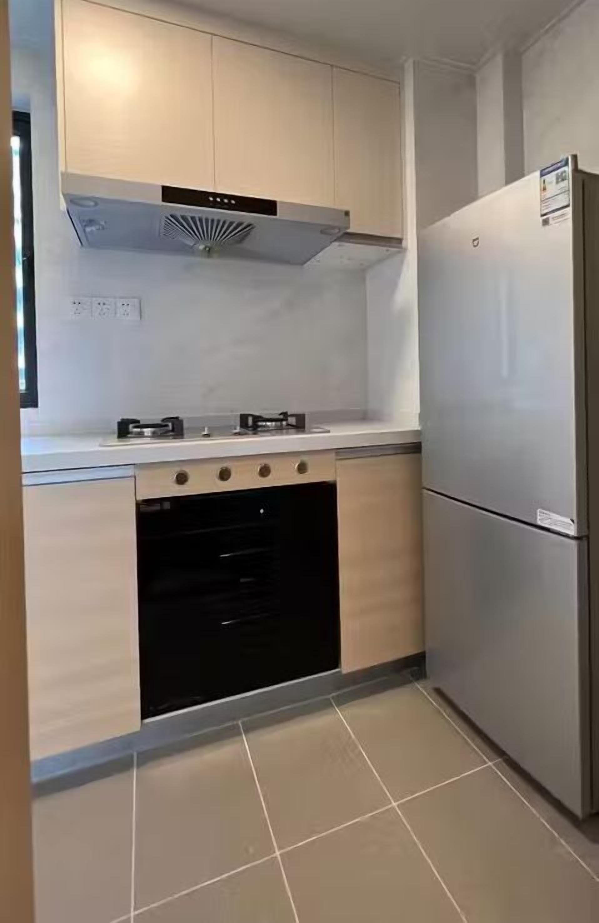 A kitchen with a built-in oven, a stainless steel refrigerator, and a modern stove.