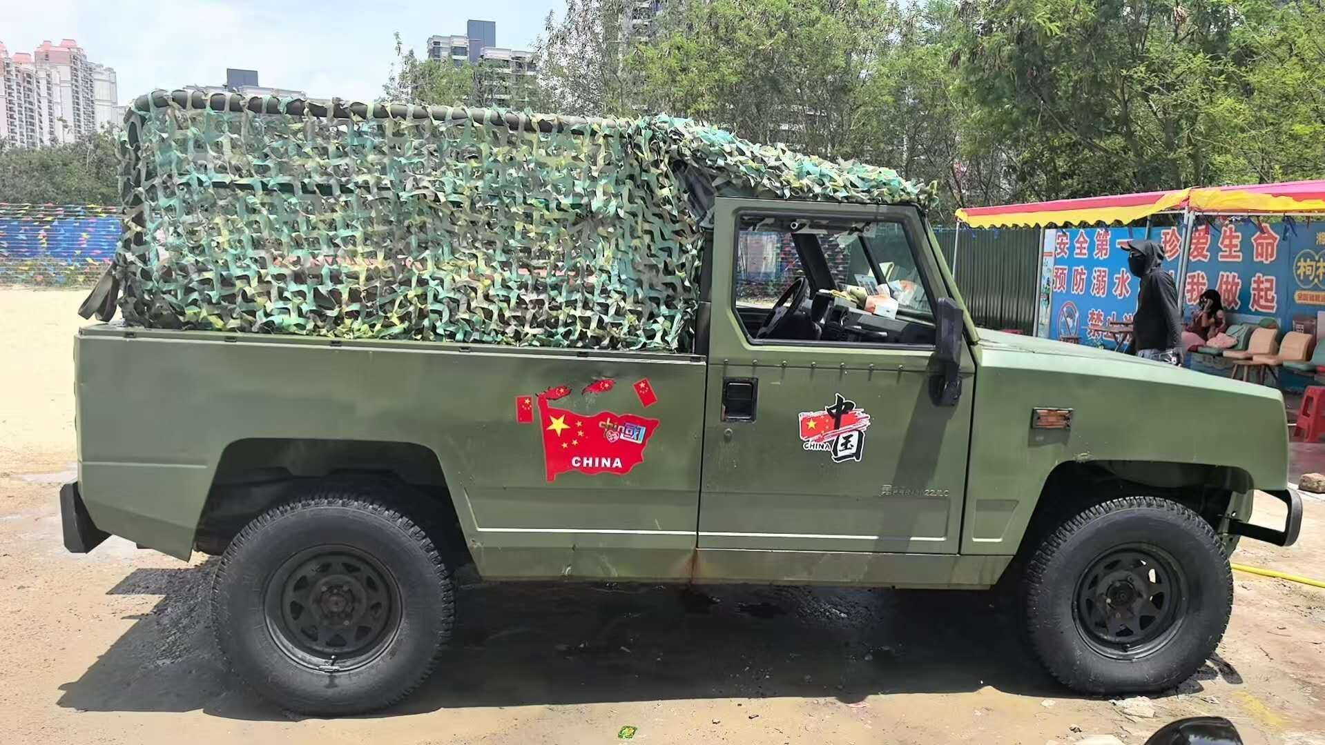 A military-style vehicle with camouflage netting and a "China" logo on the side.