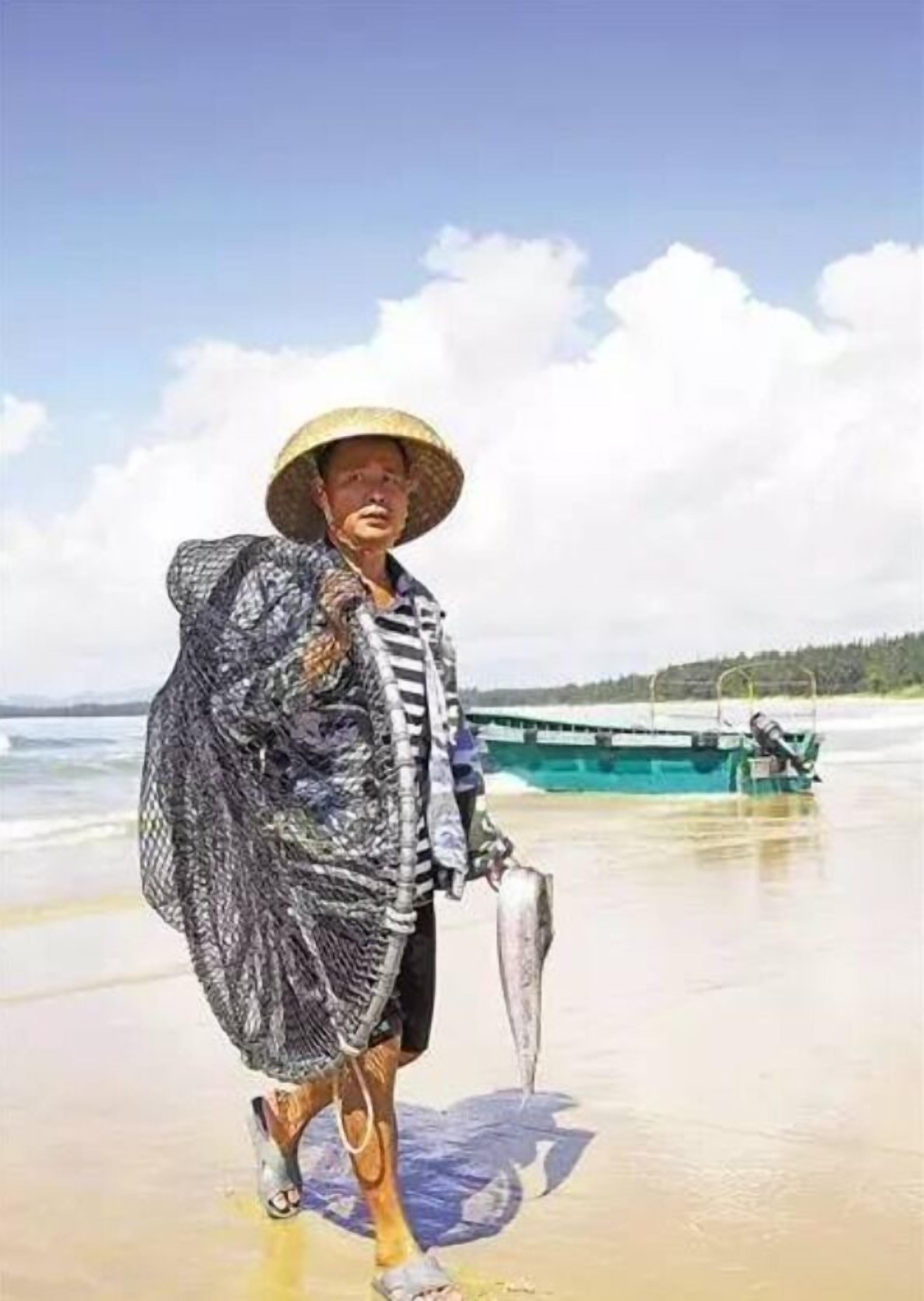 A person standing on a beach with a boat in the background.