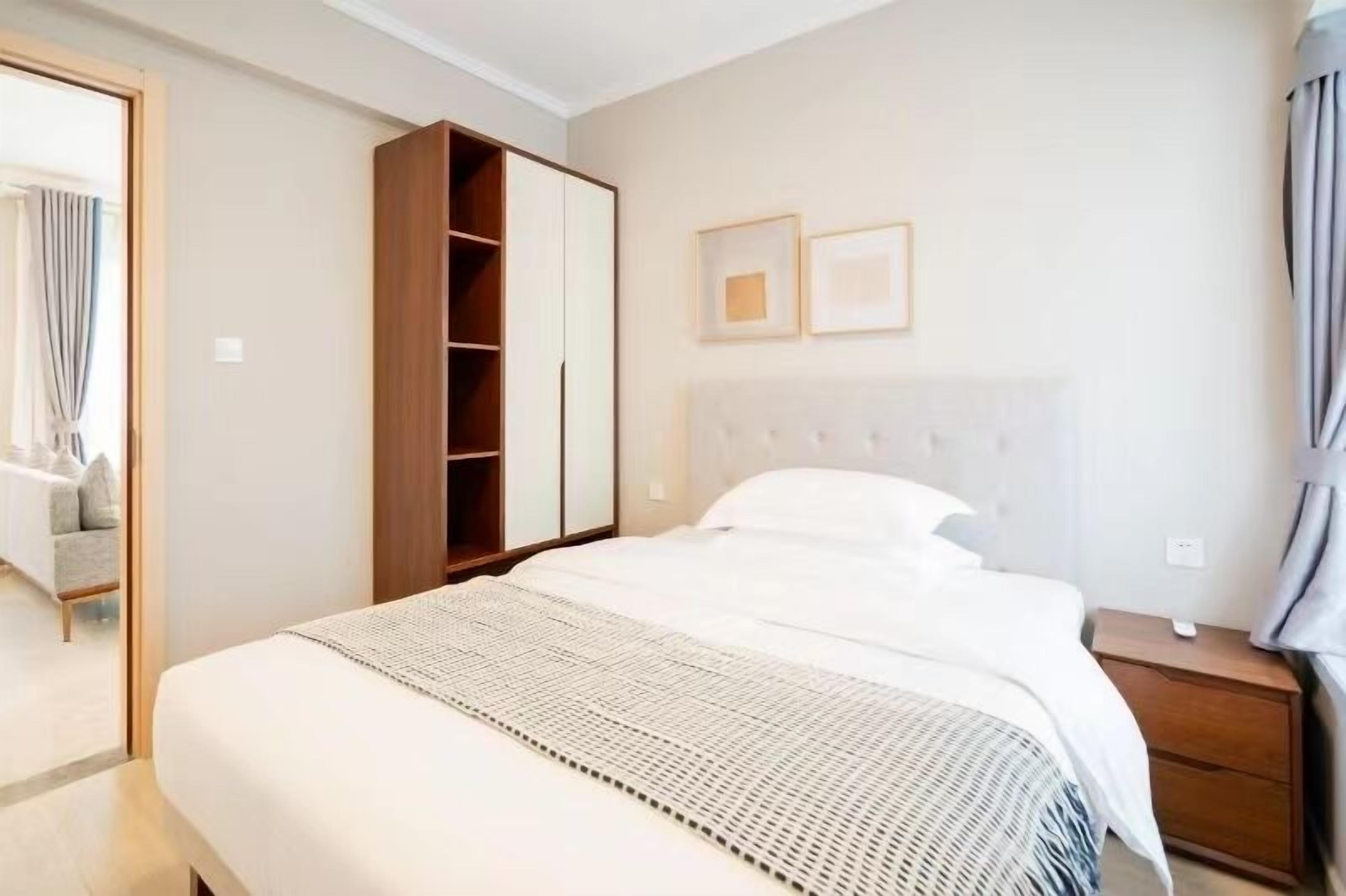 Un dormitorio moderno con una cama grande, un armario y una mesita de noche.