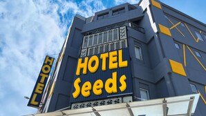 Un letrero de hotel con el nombre 'HOTEL SEEDS' en letras amarillas grandes sobre un fondo azul.