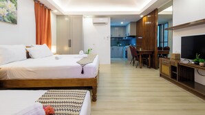 Una habitación de hotel con dos camas, una mesa de comedor y un televisor.
