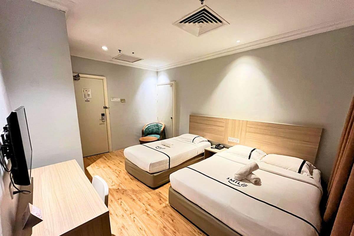 Een hotelkamer met twee bedden, een bureau, een stoel en een televisie.