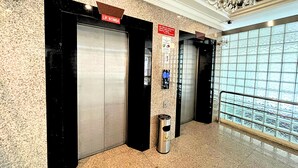 An elevator area with a trash can, a sign indicating 'LIF BOMBA', and a wall with a textured pattern. - Sky Hotel Chow Kit PWTC (Kuala Lumpur)