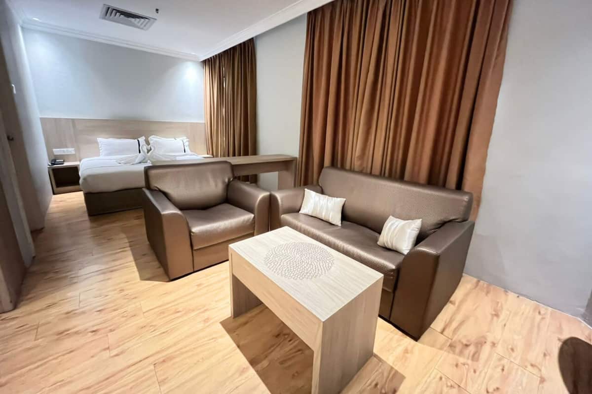 Een hotelkamer met een bed, een bank, een salontafel en een bureau.