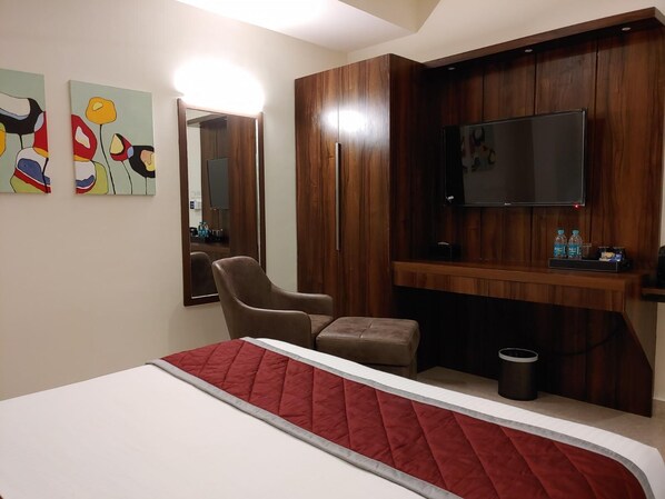 Une chambre d’hôtel avec un lit, une chaise, une télévision et un miroir.