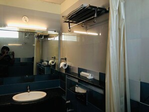 A modern bathroom with a sink, mirror, towel rack, and shower. - COASTAL GRANDCassa Times Electronic City (Bengaluru)