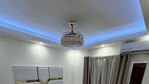 A modern bedroom with a large bed, bedside tables, a ceiling light fixture, and a window with curtains. - Casa Las América (Santo Domingo Este)