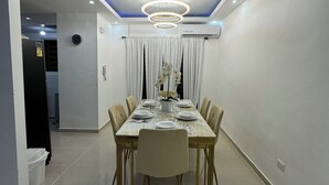 A dining area with a rectangular table set for six, surrounded by chairs. - Casa Las América (Santo Domingo Este)