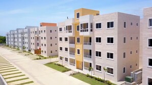 A modern residential building with multiple floors, balconies, and a well-maintained lawn area. - Casa Las América (Santo Domingo Este)