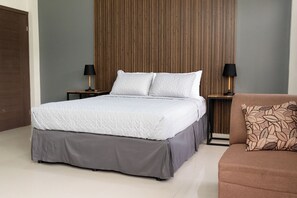 Un dormitorio moderno con una cama grande, dos mesitas de noche con lámparas, un sofá marrón y un panel de pared de madera.