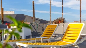 Dos sillones amarillos, una mesita blanca y plantas en macetas en una terraza en la azotea.