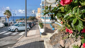 Vista de una calle con coches aparcados, un paso de peatones y un edificio con señalización.