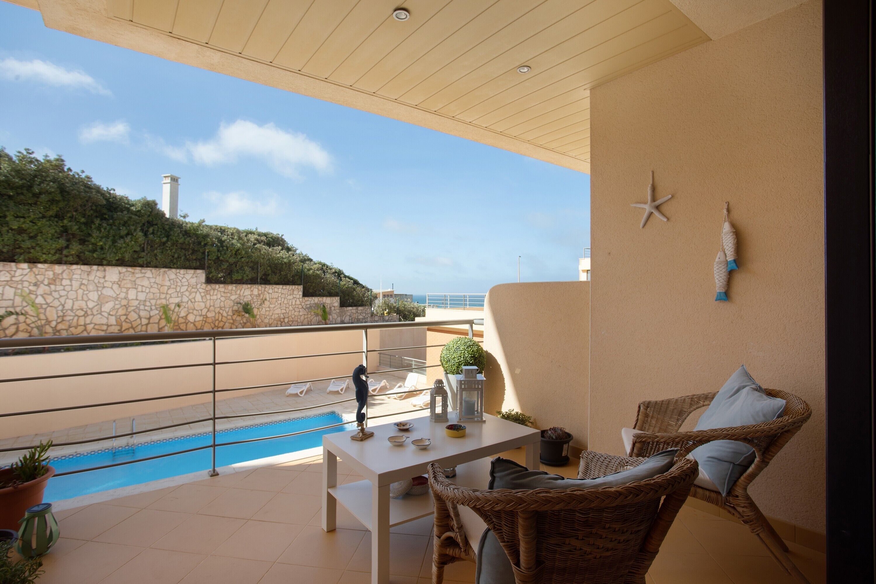 Un balcón con piscina, muebles de mimbre y una decoración con forma de estrella de mar.