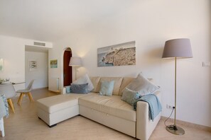 A modern living room with a sofa, a floor lamp, and a painting on the wall.