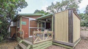 A small wooden cabin with a green deck, a door labeled 'NEMO,' and two flower planters on the deck. - Mobile Home 'Chalet Confort Proche De La Mer' with Shared Pool, Private Terrace and Air Conditioning (Pianottoli-Caldarello)