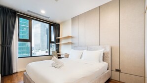 A modern hotel room with a large bed, a desk, and a view of the cityscape through the window. - Salute de Madison Luxury Apt District 1 (Ho Chi Minh City)