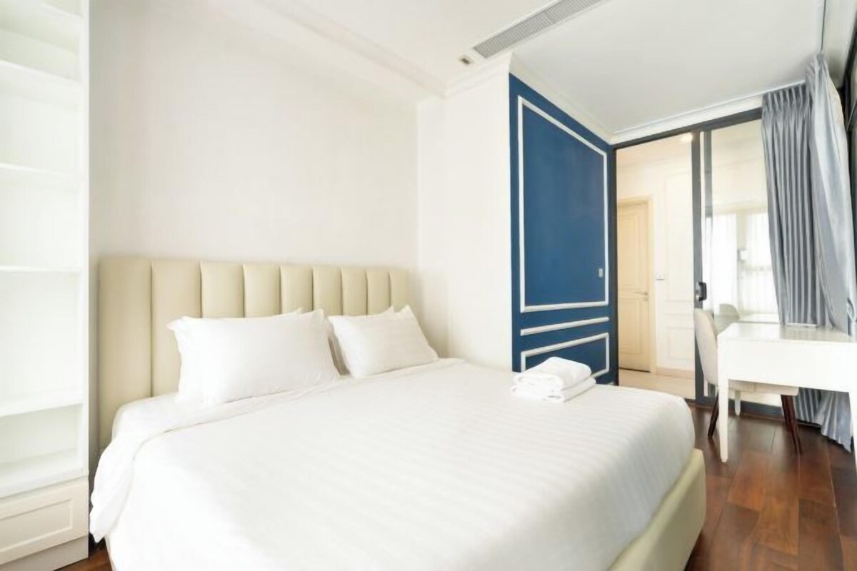 Hotellihuone, jossa on suuri sänky, työpöytä ja ovi, joka johtaa toiseen huoneeseen.