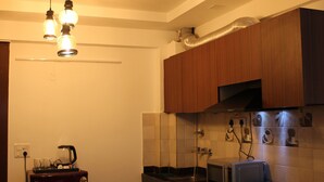 Eine Küche mit Holzschränken, einem Kühlschrank, einer Kaffeemaschine und einer Mikrowelle.
