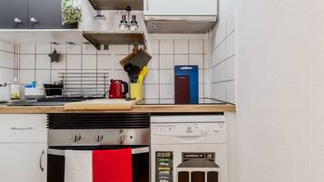 A kitchen with a dishwasher, oven, and various kitchen utensils.